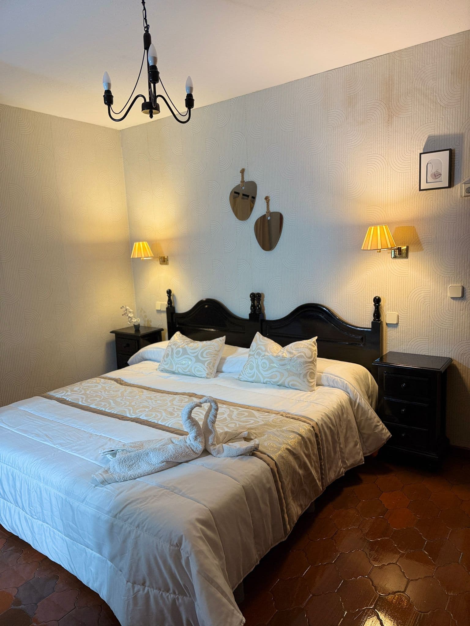 Habitación matrimonial con iluminación cálida y cabecero clásico.